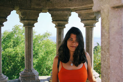 Young woman looking down while standing at old ruin