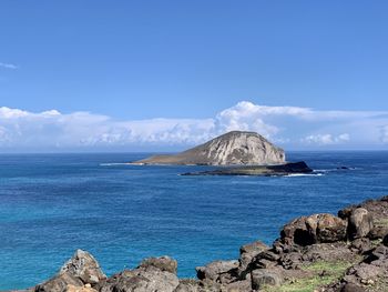 Scenic view of sea and rocks against blue sky