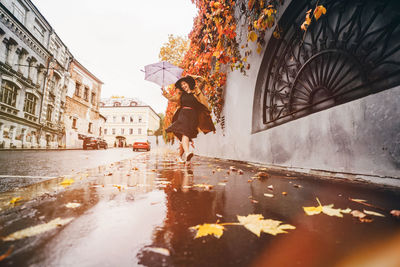 Rear view of woman standing in puddle