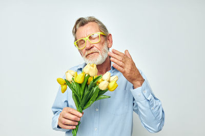 Portrait of young woman holding flower against white background