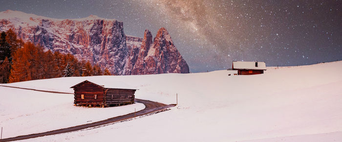 House on snowcapped mountain against sky