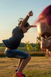 Woman with arms raised on field against sky