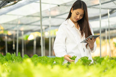 Young woman standing against plants