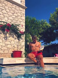 Man sitting by swimming pool against trees