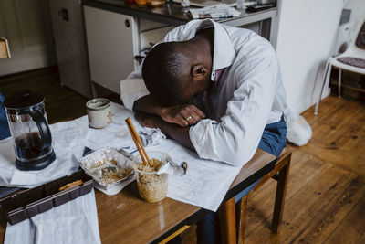 Depressed male entrepreneur with head down on table at home