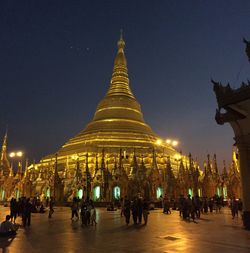 People in illuminated temple against sky at night