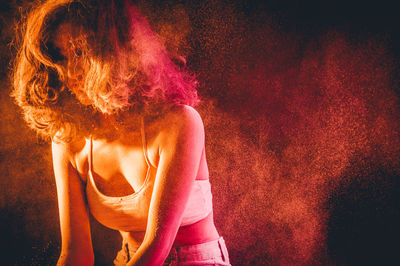 Young woman surrounded by powder paint against black background