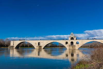 Arch bridge over river against blue sky