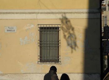 Man standing by window on building wall