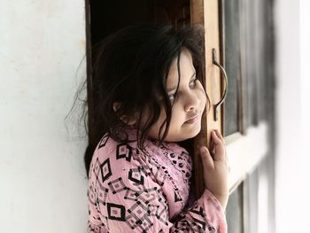 Portrait of girl looking through window