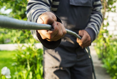 Midsection of man holding rope outdoors