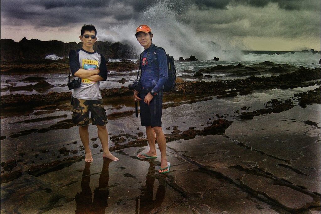 full length, lifestyles, casual clothing, leisure activity, person, sky, standing, water, beach, sea, shore, young men, cloud - sky, vacations, sand, front view, childhood, rock - object