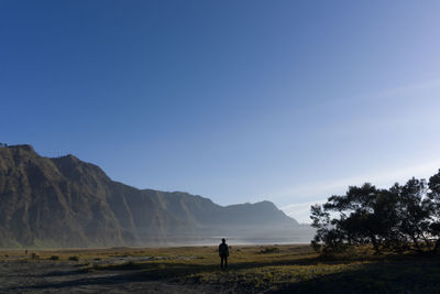 Man standing on mountain against clear sky mount bromo