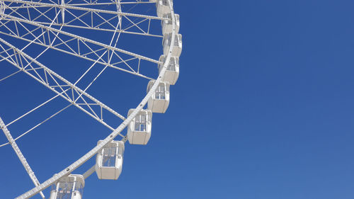 Low angle view of ferris wheel against clear blue sky