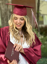 Portrait of young woman wearing graduation gown standing outdoors