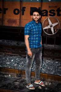 Portrait of young man standing against wall