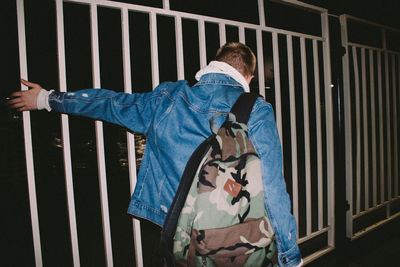Rear view of man standing by railing of building