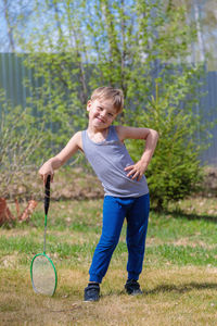 A fair-haired child plays badbinton on the lawn