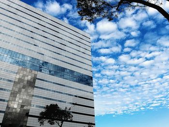 Low angle view of modern building against cloudy sky