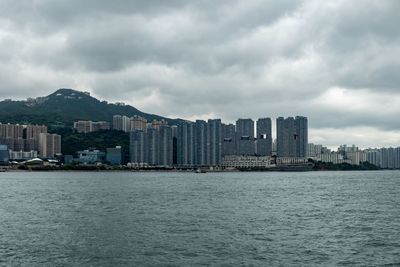 Sea by buildings against sky in city