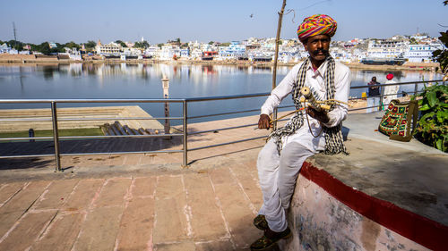 Man playing musical instrument against lake in city