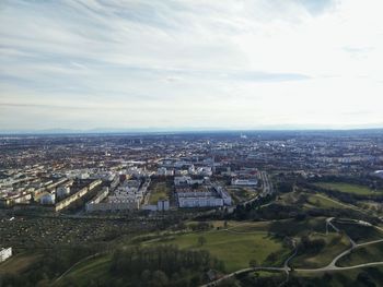 Aerial view of cityscape against cloudy sky