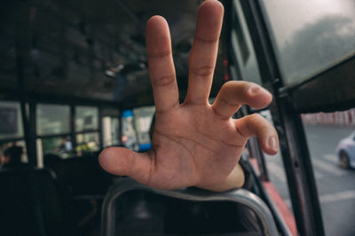 Cropped hand by window in bus