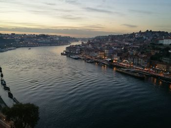 River amidst cityscape against sky during sunset