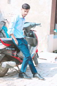 Full length portrait of young man holding cigarette in city