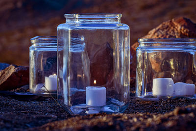 Clear glass candle lanterns outdoors in rock garden