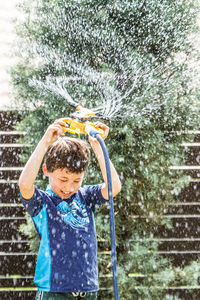 Smiling boy playing with garden hose at yard