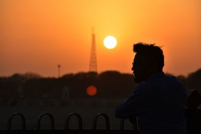 Rear view of silhouette man standing at sunset