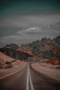 Road leading towards mountains against sky