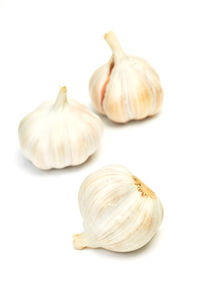 Close-up of fresh garlic bulbs over white background