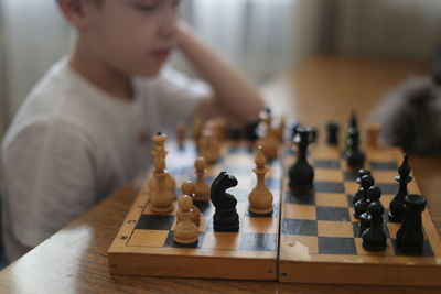 Midsection of boy playing chess at home