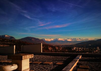 Railroad tracks by mountains against blue sky