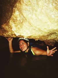 Smiling young woman in stream under cave