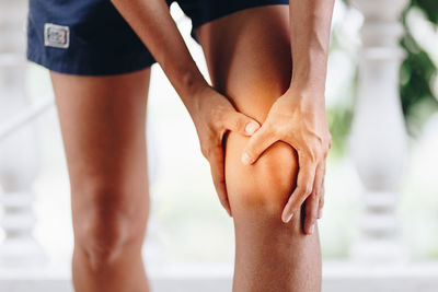 Close-up of woman with knee pain while standing outdoors