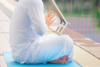 Low section of woman sitting at swimming pool
