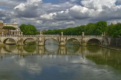 Arch bridge over river against sky