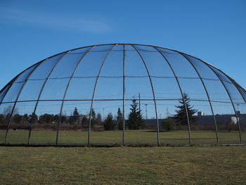 Low angle view of field seen through fence