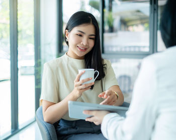 Young woman using mobile phone while sitting at home