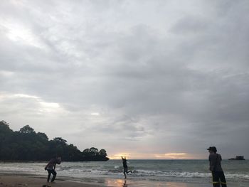 People standing on beach against sky