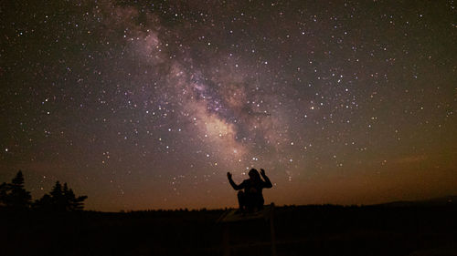 Silhouette person standing on field against sky at night