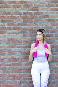 Young woman standing against brick wall