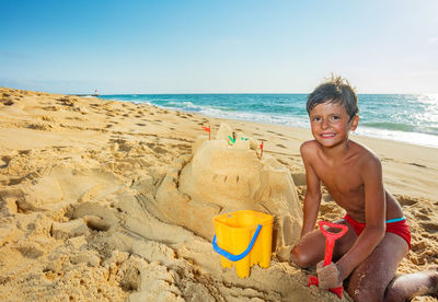 Portrait of boy playing at beach against clear sky