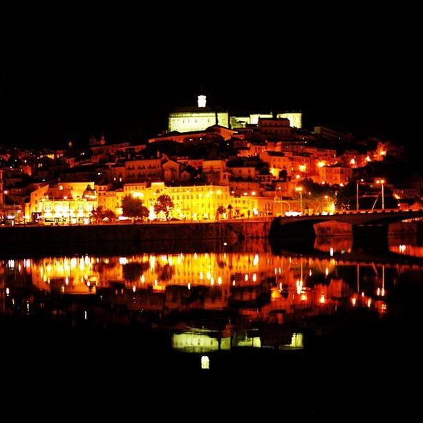 illuminated, night, architecture, built structure, building exterior, water, river, city, reflection, bridge - man made structure, waterfront, connection, transportation, cityscape, sky, city life, high angle view, travel destinations, clear sky, outdoors