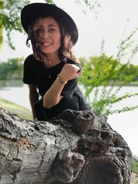 Portrait of gesturing by tree trunk in park