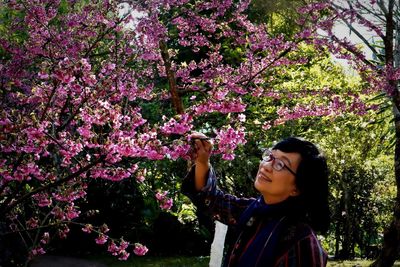 Close-up of smiling senior woman holding flower at park