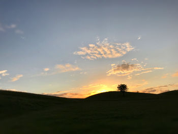 Scenic view of silhouette field against sky at sunset